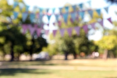 Photo of Blurred view of colorful bunting flags in park. Party decor