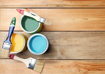Brushes and paint cans on wooden background, flat lay