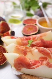 Photo of Tasty melon, jamon and figs served on table, closeup