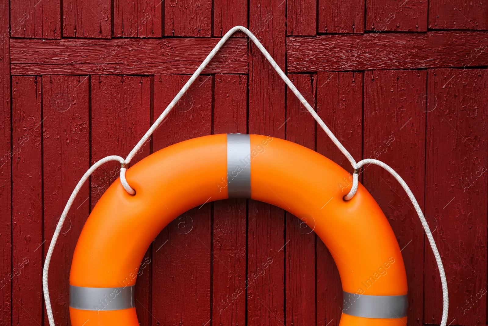 Photo of Orange life buoy hanging on red wooden wall