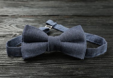 Photo of Stylish blue bow tie on black wooden background, closeup