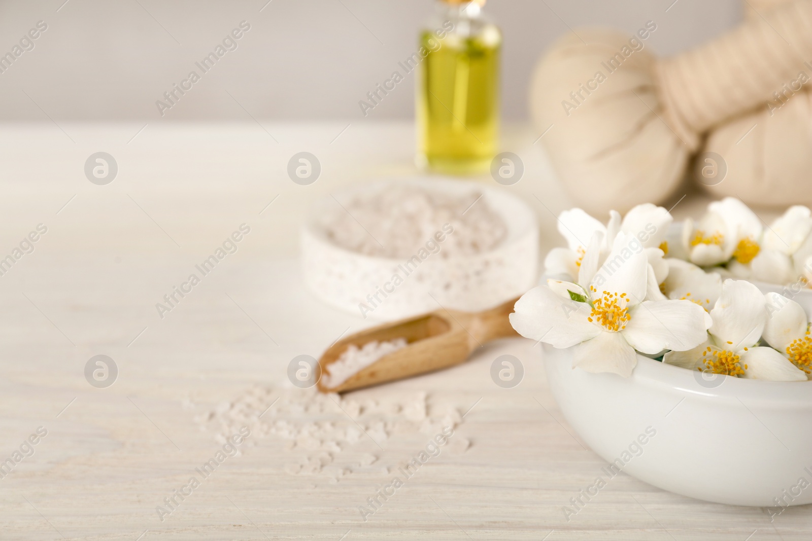 Photo of Mortar with beautiful jasmine flowers and pestle on white wooden table, closeup. Space for text