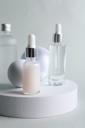 Stylish presentation of bottles with cosmetic serums on light grey background