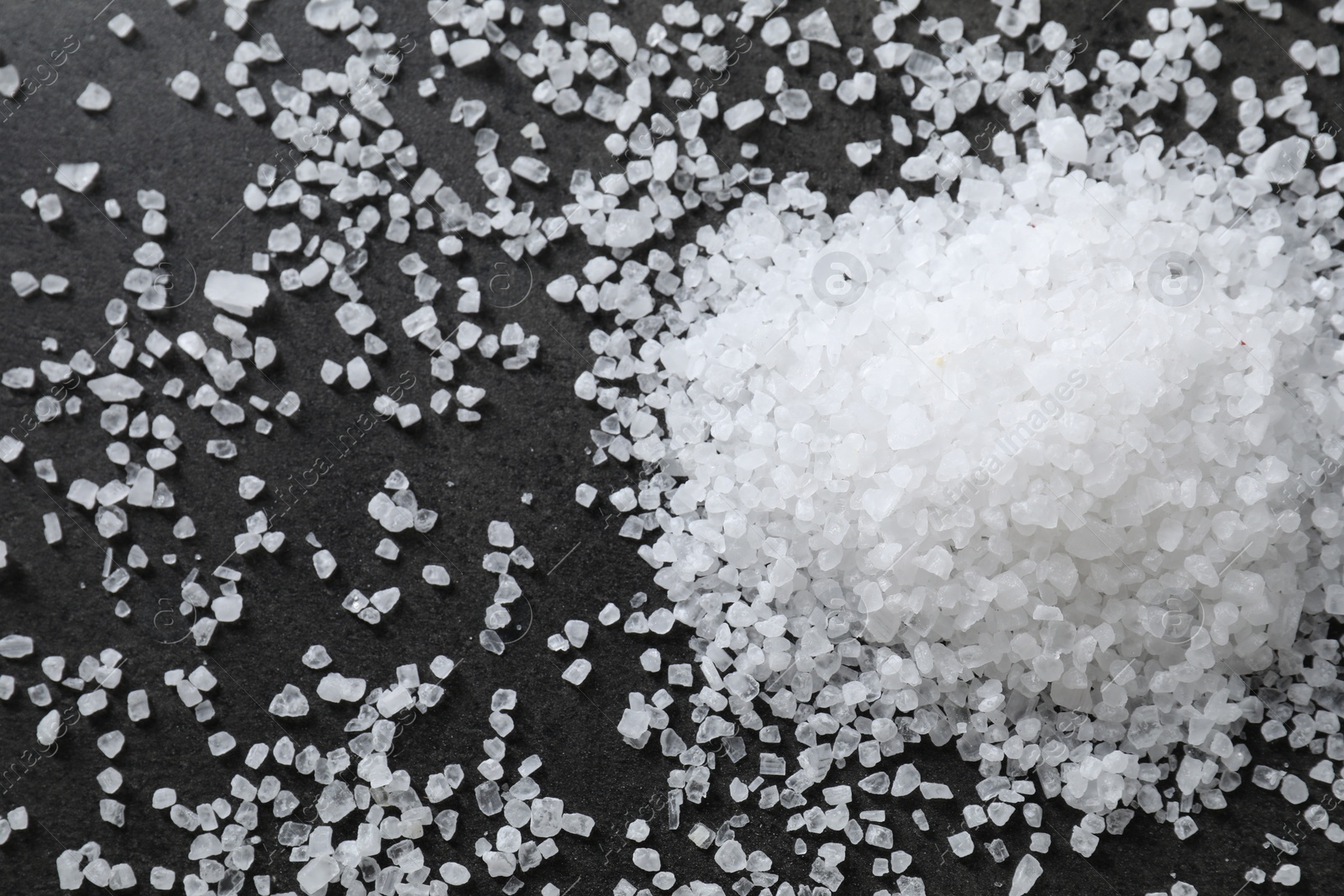 Photo of Heap of natural salt on black table, top view