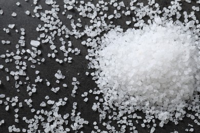 Photo of Heap of natural salt on black table, top view