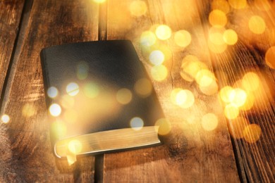 Closed Bible on wooden table, bokeh effect