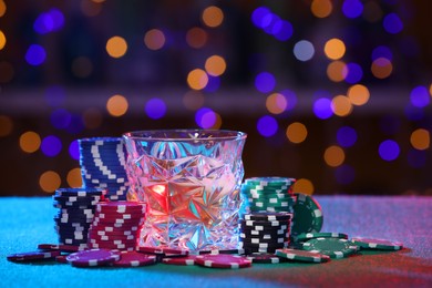 Photo of Alcohol drink and casino chips on table against blurred lights