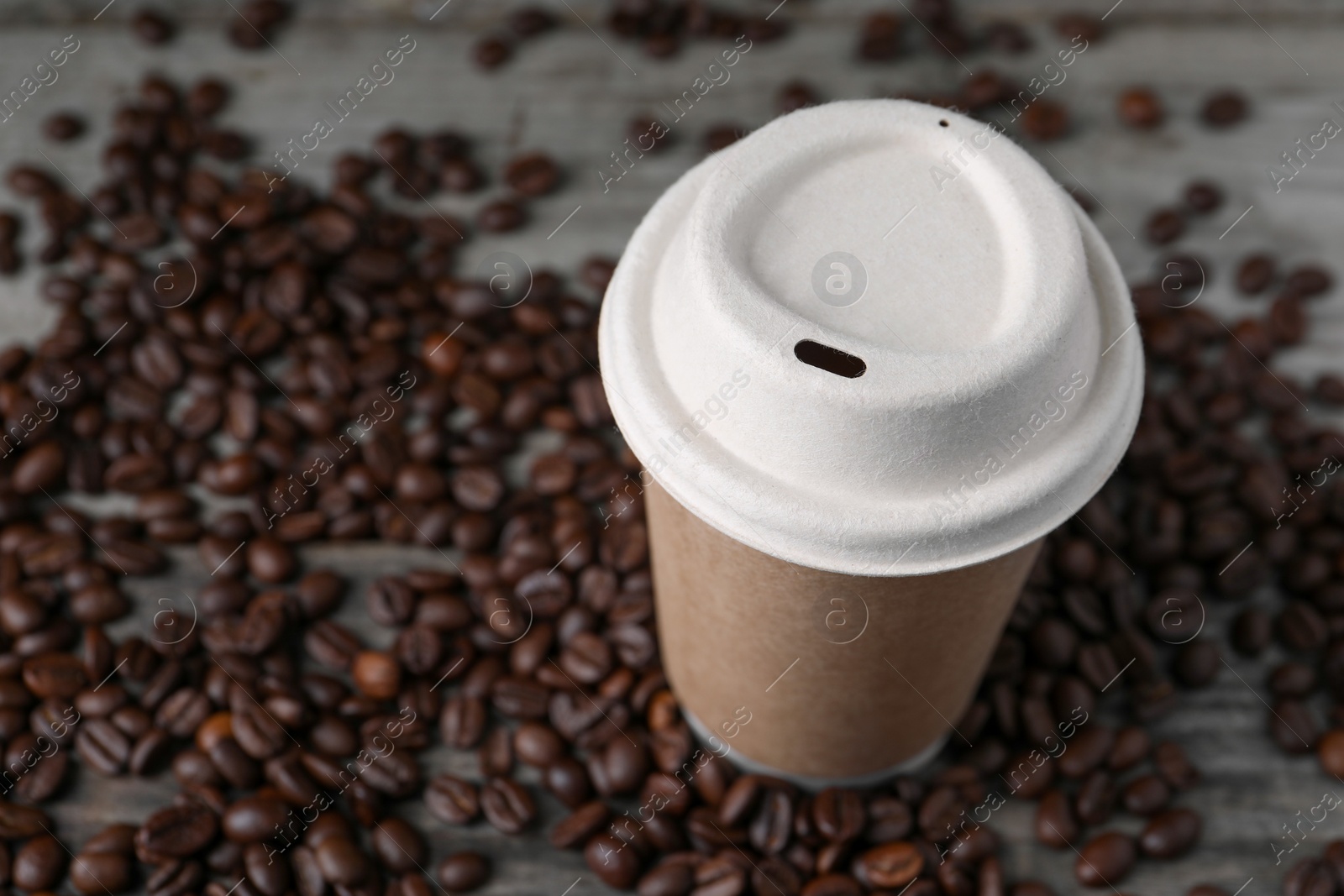 Photo of Coffee to go. Paper cup and roasted beans on table, closeup. Space for text