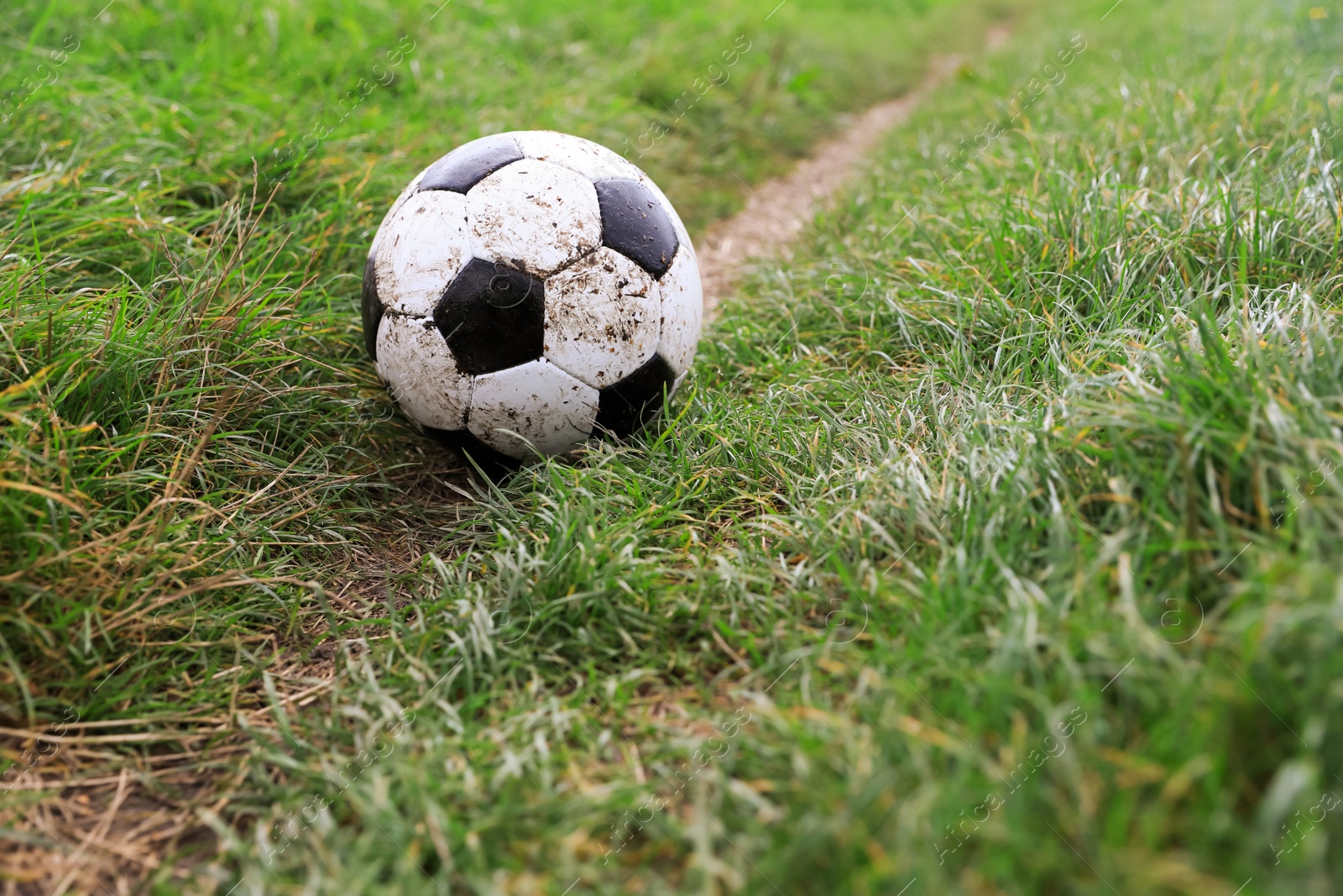 Photo of Dirty soccer ball on green grass outdoors, space for text