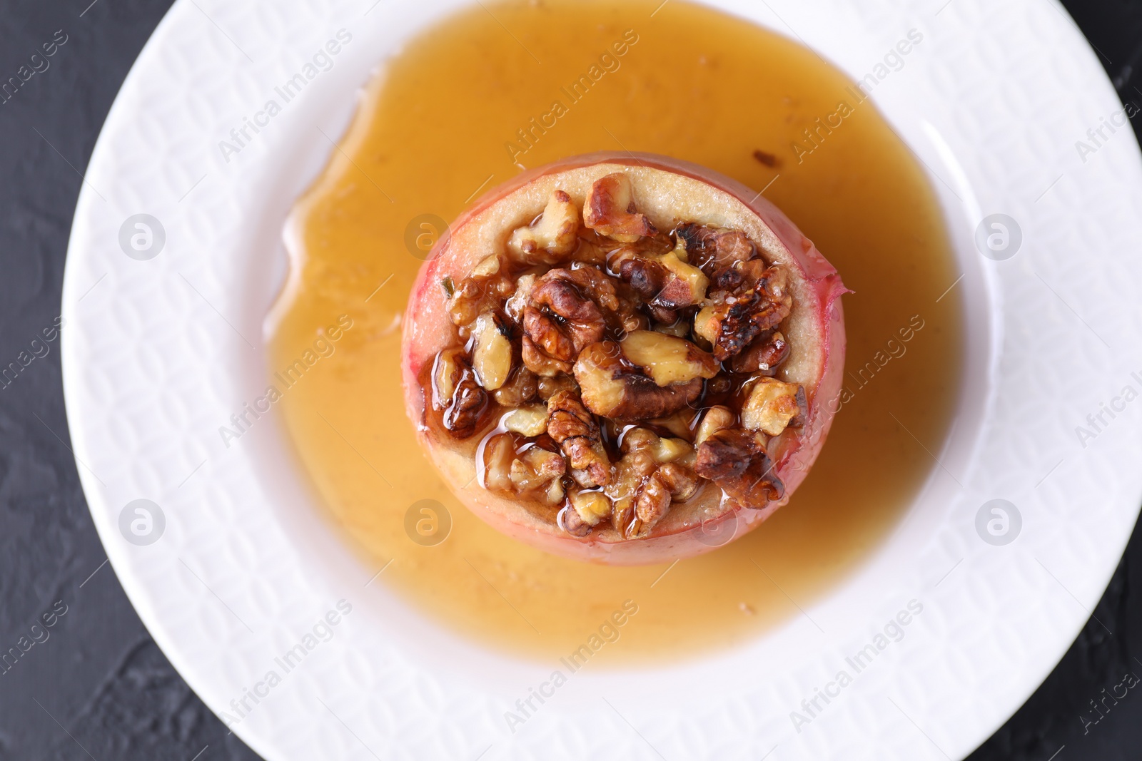 Photo of Tasty baked apple with nuts and honey on gray table, top view