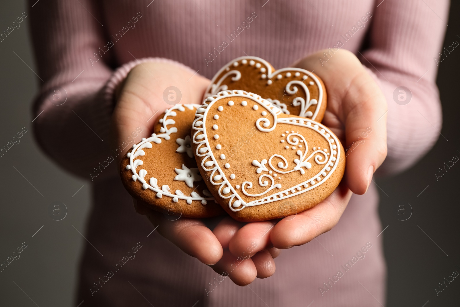 Photo of Woman holding tasty heart shaped gingerbread cookies, closeup