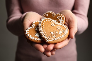 Woman holding tasty heart shaped gingerbread cookies, closeup