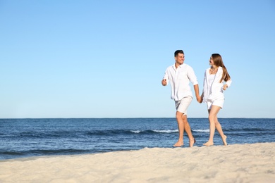 Photo of Lovely couple walking on beach. Space for text