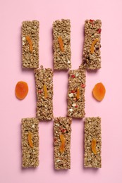 Photo of Tasty granola bars on pink background, flat lay