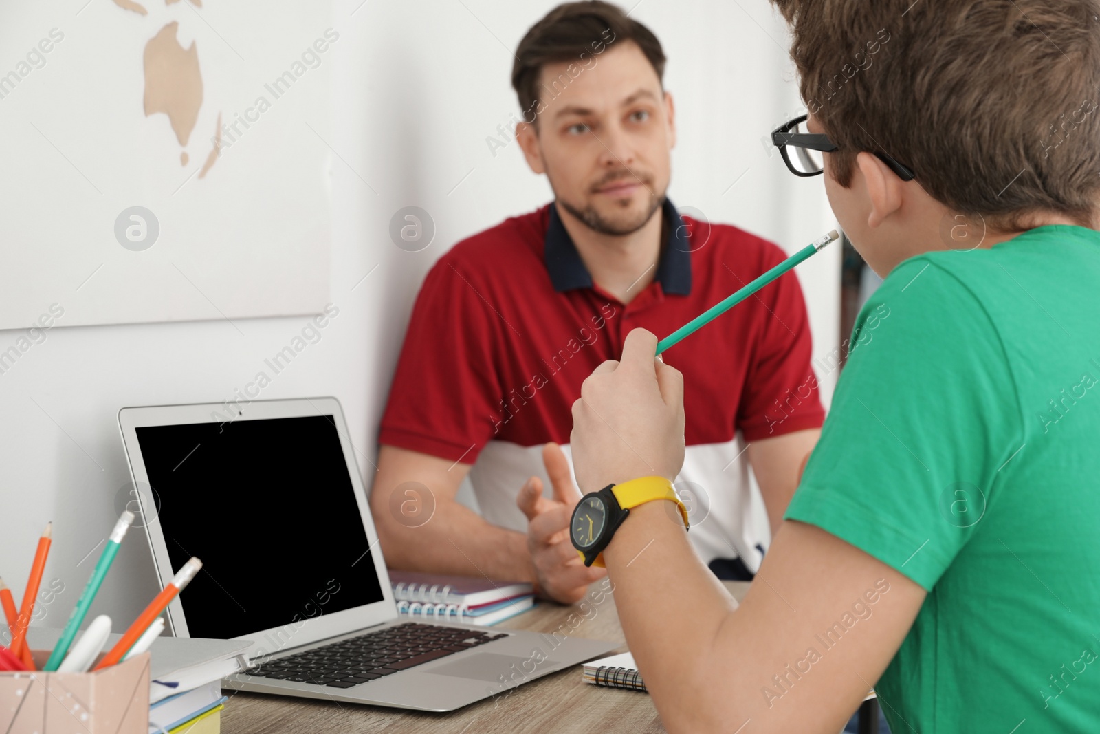 Photo of Father helping his teenager son with homework indoors