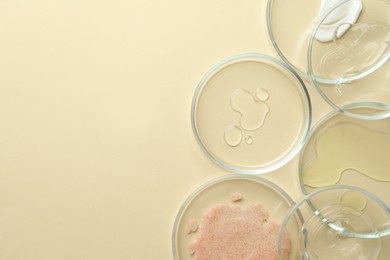 Photo of Many Petri dishes and cosmetic products on beige background, flat lay. Space for text