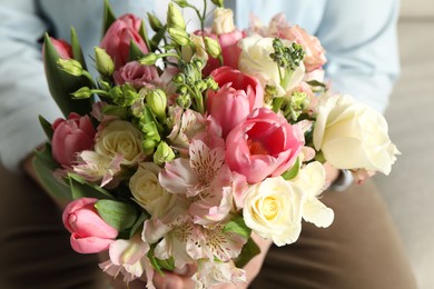 Man holding bouquet of beautiful flowers indoors, closeup