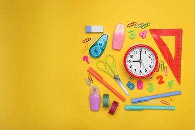 Photo of Flat lay composition with different school stationery and alarm clock on yellow background, space for text. Back to school