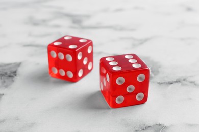 Two red game dices on white marble table, closeup