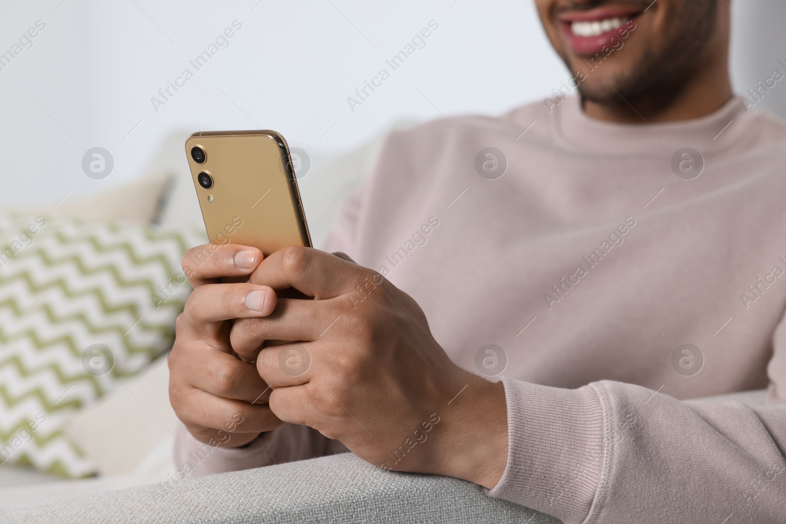 Photo of Happy man sending message via smartphone indoors, closeup