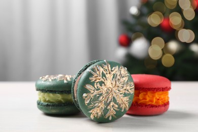 Photo of Different decorated Christmas macarons on white table indoors