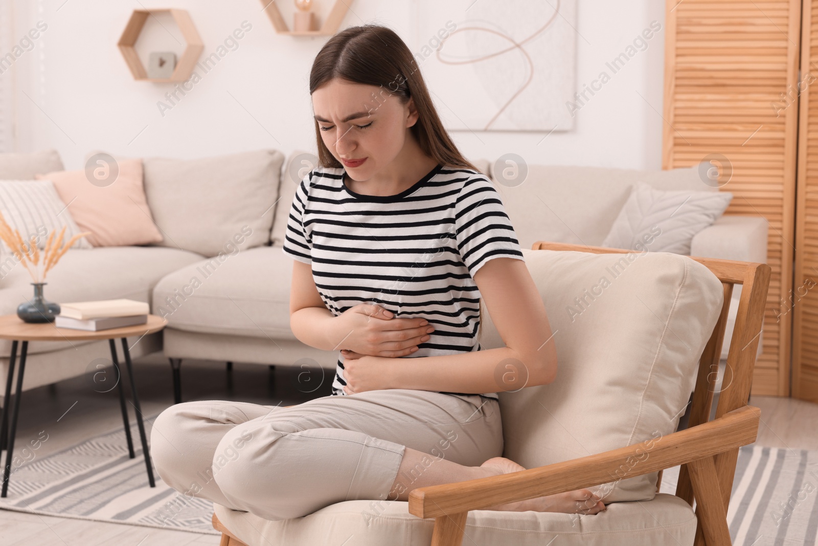 Photo of Young woman suffering from stomach pain at home