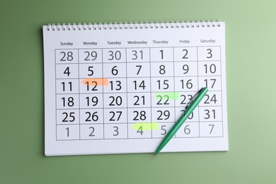 Timetable. Calendar page with marked dates and pen on green background, top view