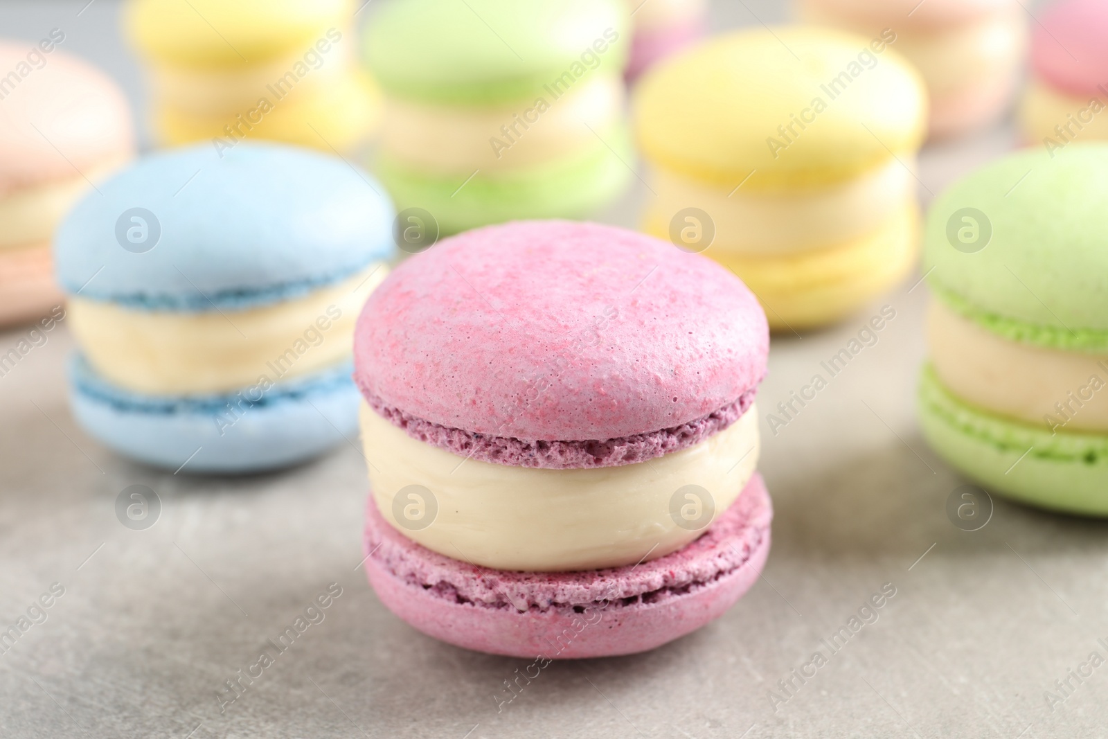 Photo of Many delicious colorful macarons on grey table, closeup