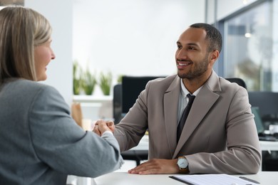 Lawyer shaking hands with client at table in office