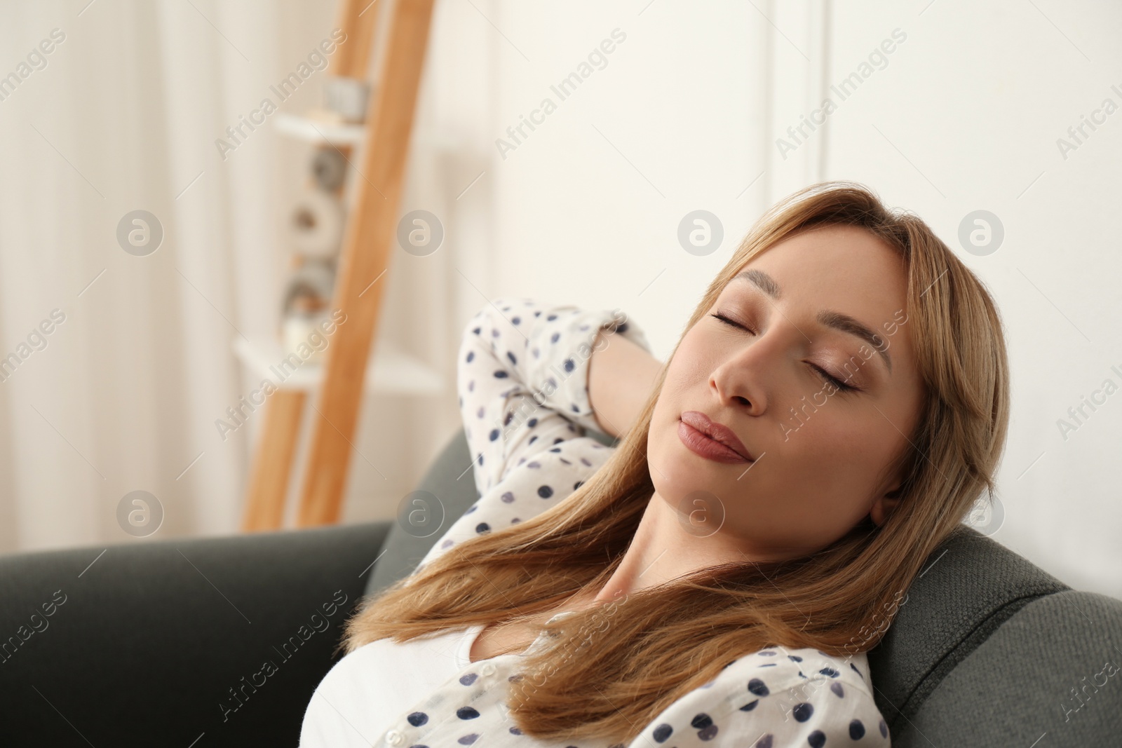 Photo of Beautiful young woman relaxing on sofa at home, space for text