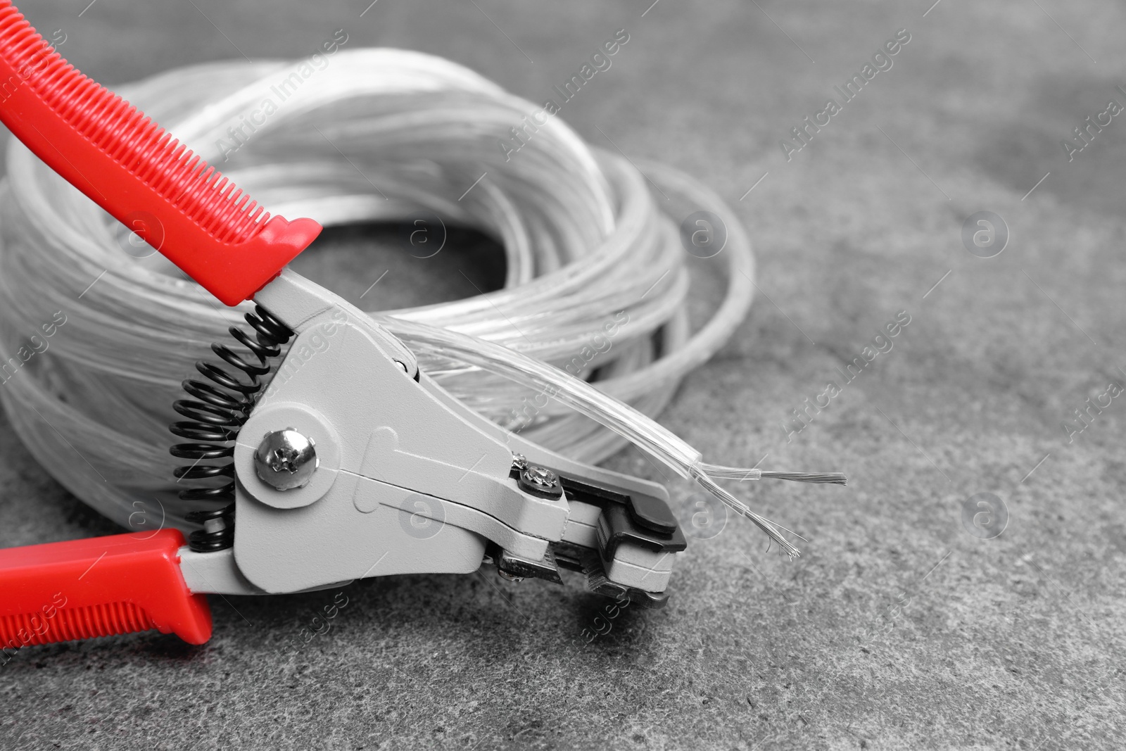 Photo of Cutters and cable with stripped wire on light gray textured table, closeup