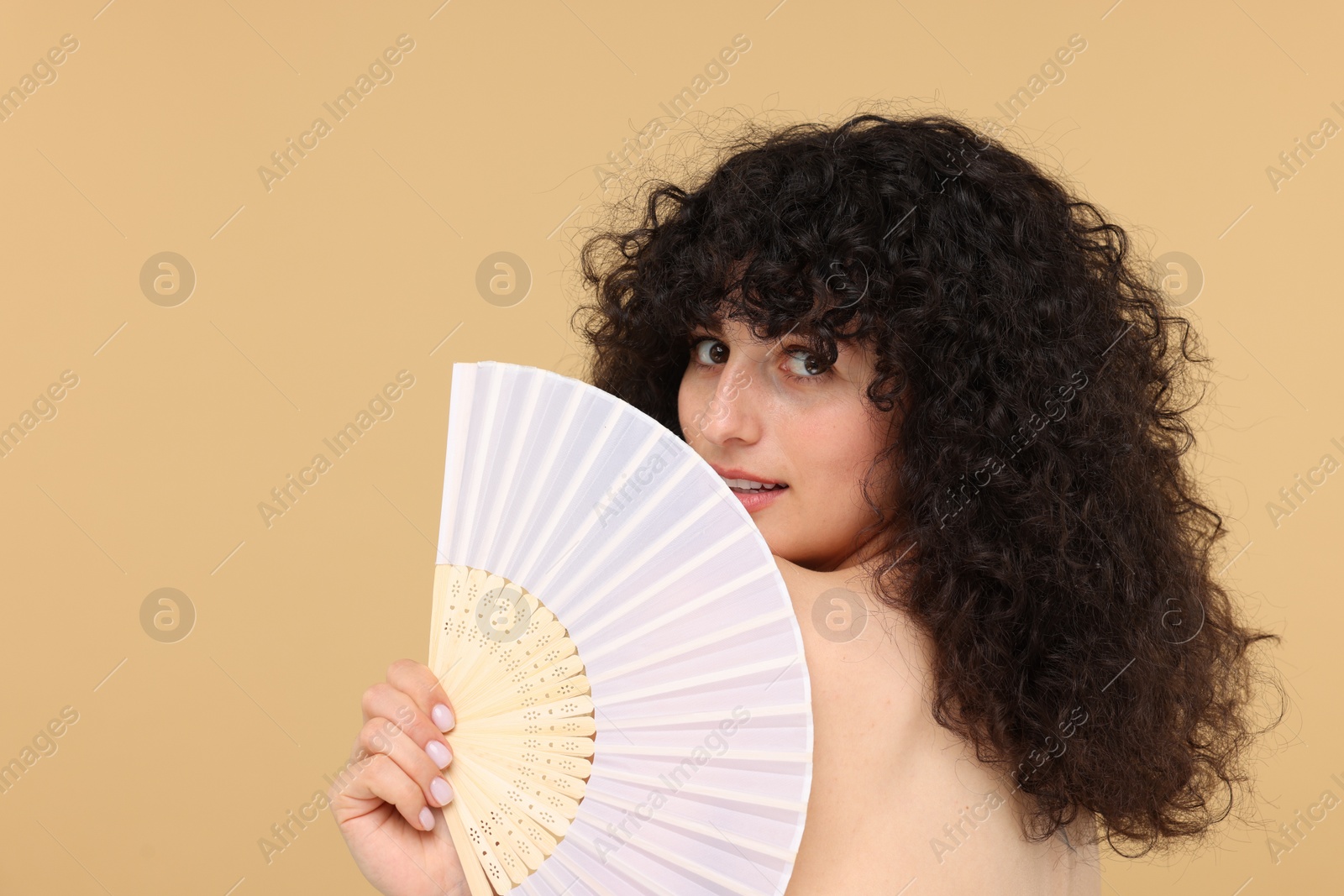 Photo of Woman holding hand fan on beige background. Space for text