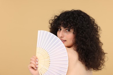 Photo of Woman holding hand fan on beige background. Space for text