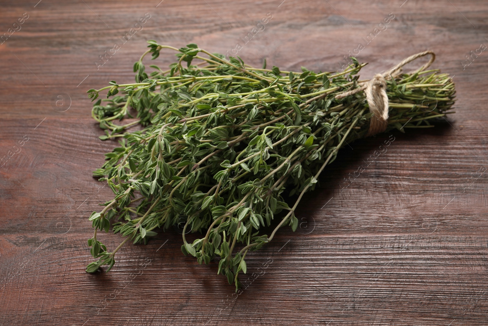 Photo of Bunch of aromatic thyme on wooden table