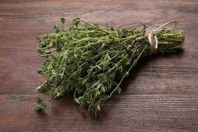 Photo of Bunch of aromatic thyme on wooden table