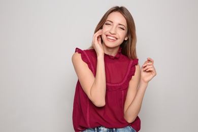 Photo of Portrait of beautiful smiling woman in stylish clothes on light background