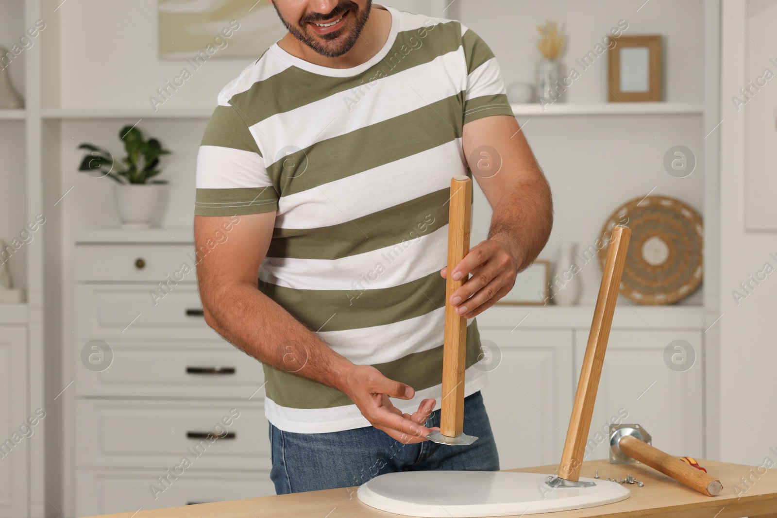Photo of Man assembling furniture at table in room, closeup