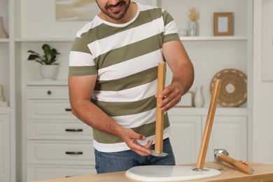 Photo of Man assembling furniture at table in room, closeup