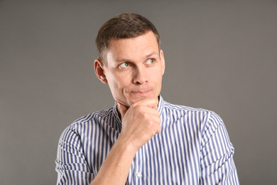 Photo of Thoughtful man in casual outfit on grey background