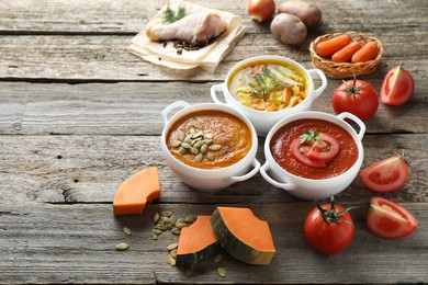 Photo of Tasty broth, cream soups in bowls and ingredients on old wooden table. Space for text