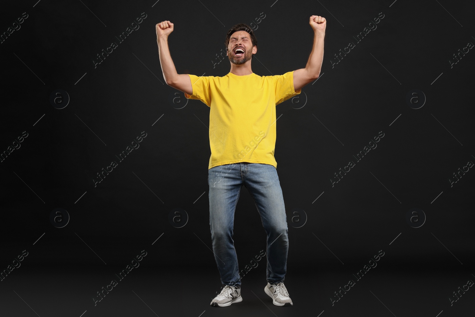 Photo of Emotional sports fan celebrating on black background