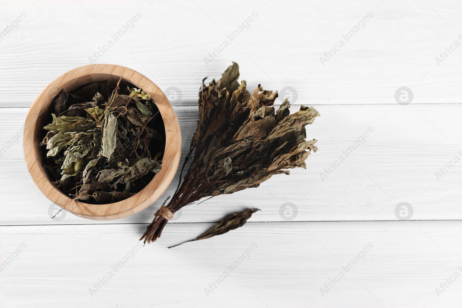 Photo of Bowl with dry basil on white wooden table, flat lay. Space for text