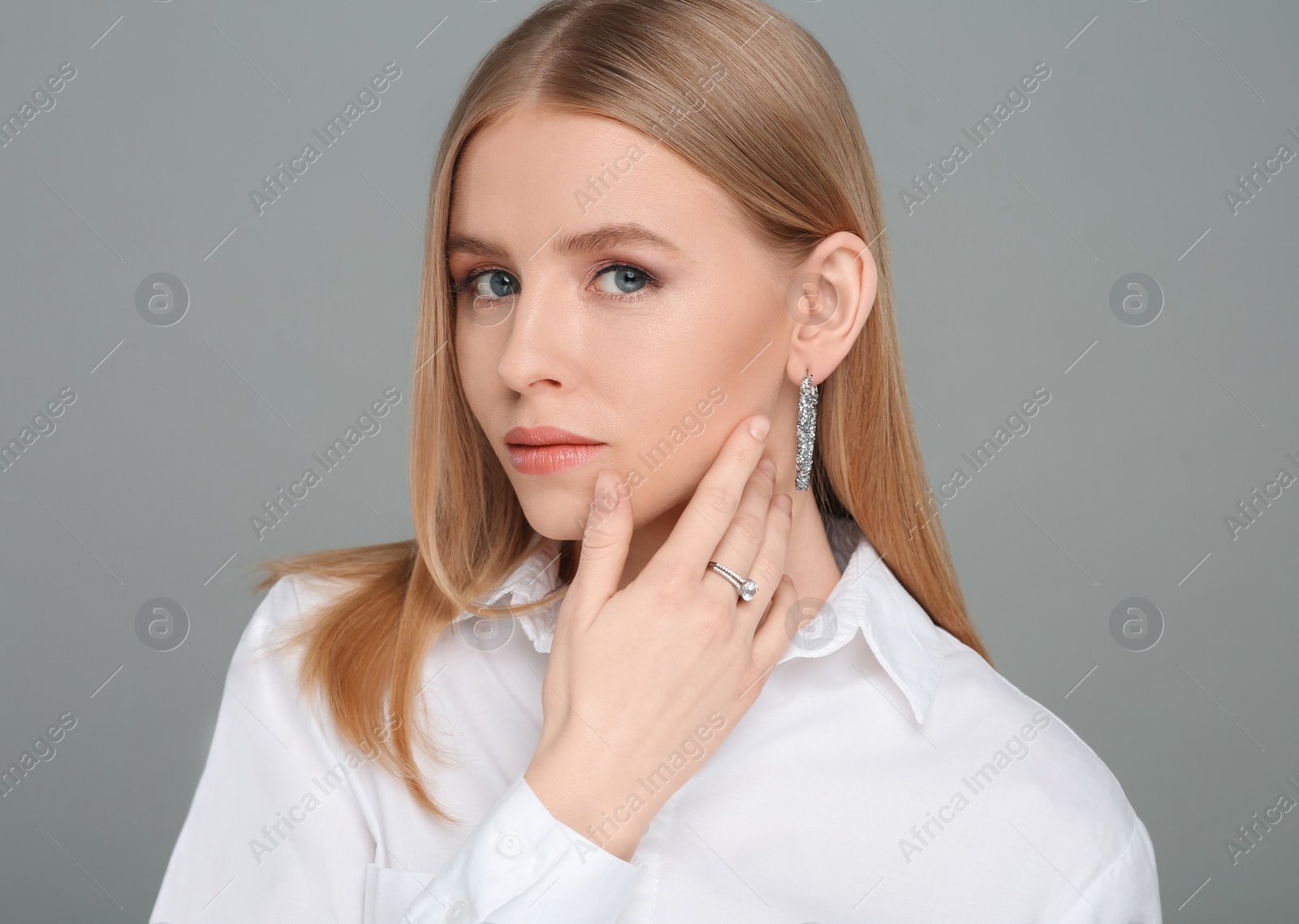 Photo of Beautiful young woman with elegant jewelry on gray background