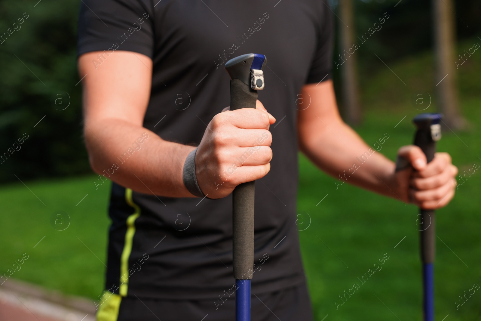 Photo of Man practicing Nordic walking with poles outdoors, closeup