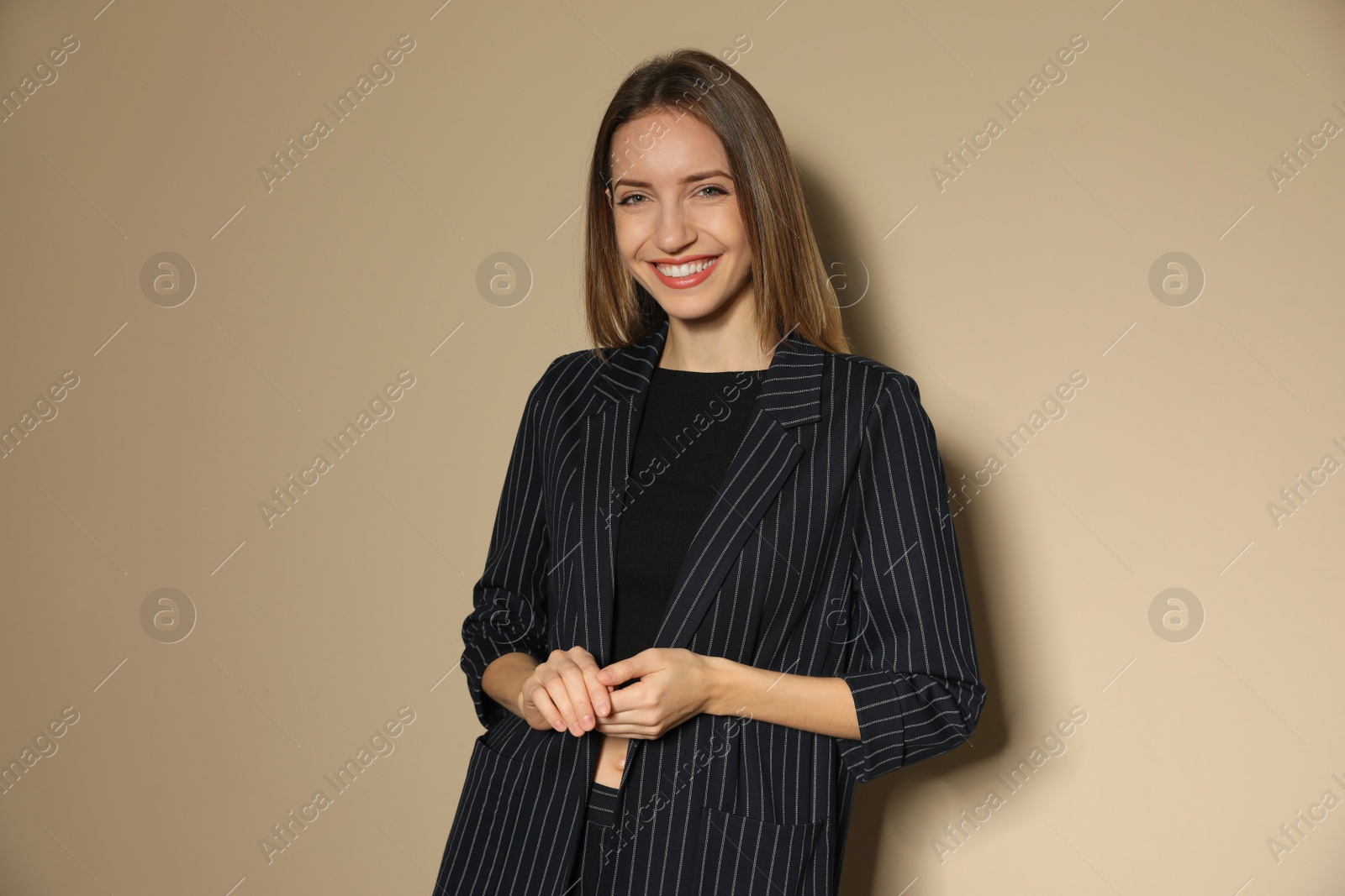 Photo of Portrait of beautiful young woman in fashionable suit on beige background. Business attire