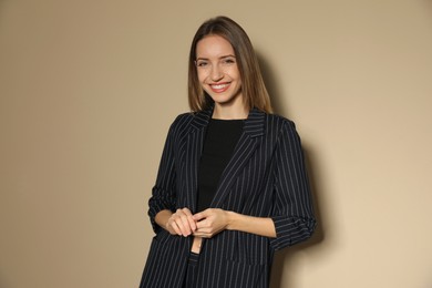 Portrait of beautiful young woman in fashionable suit on beige background. Business attire