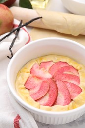 Baking dish with fresh dough and apples on table