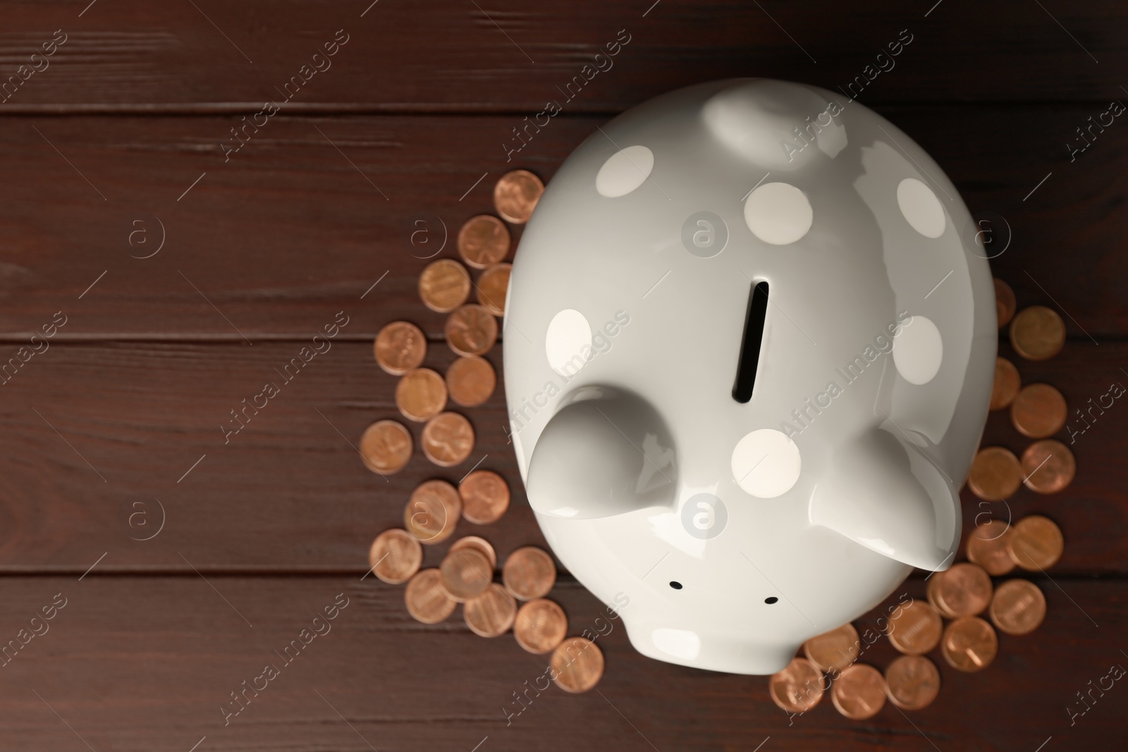 Photo of Ceramic piggy bank and coins on wooden table, flat lay. Space for text