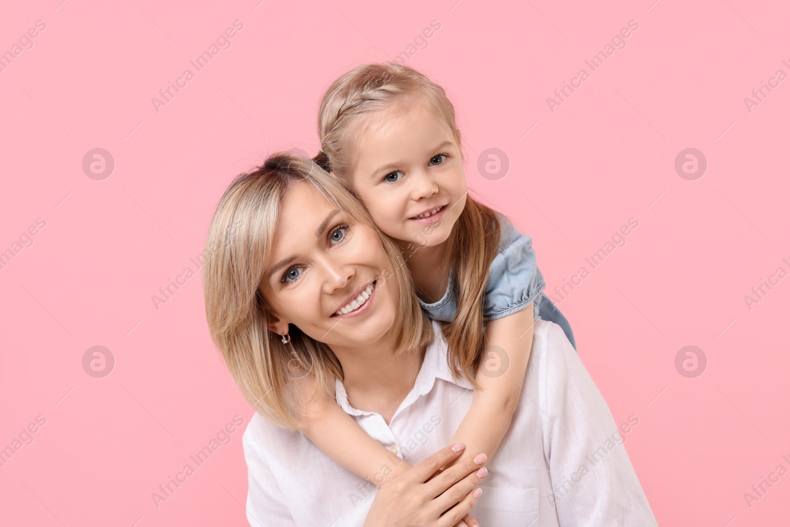 Photo of Daughter hugging her happy mother on pink background