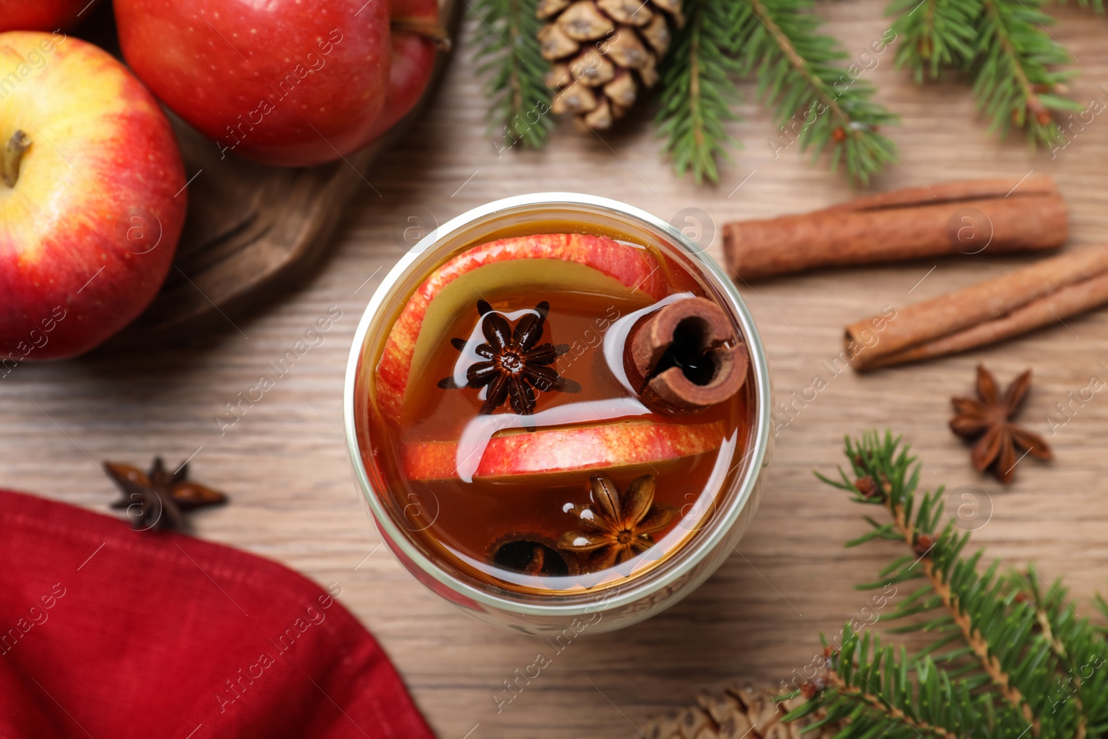 Photo of Hot mulled cider, ingredients and fir branches on wooden table, flat lay